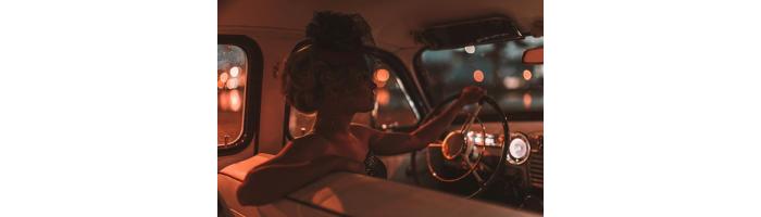 Woman in retro car at night with city lights