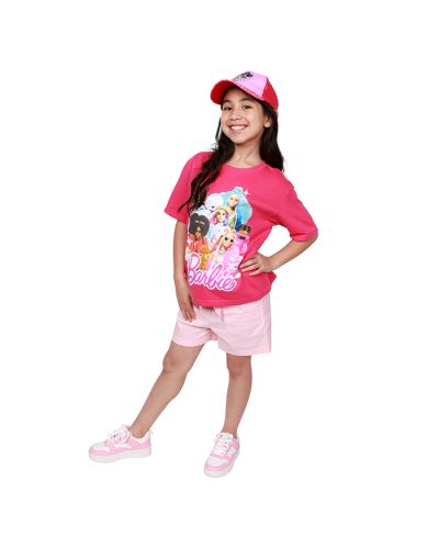 Pre-teen girl model wearing Barbie branded baseball cap with logo print on the bill, a hot pink Barbie branded t-shirt with a large image that features a collage of Barbie doll toys, light pink drawstring paperbag shorts and white and pink faux leather la