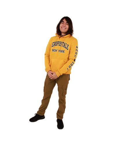 The male model wears the yellow "Aero" Pull Over Aeropostale Hoodie paired with the rugged "X-Ray" Twill Straight Leg Cargo Pants and black "American Exchange" Elastic Lace-up Athletic Sneakers.